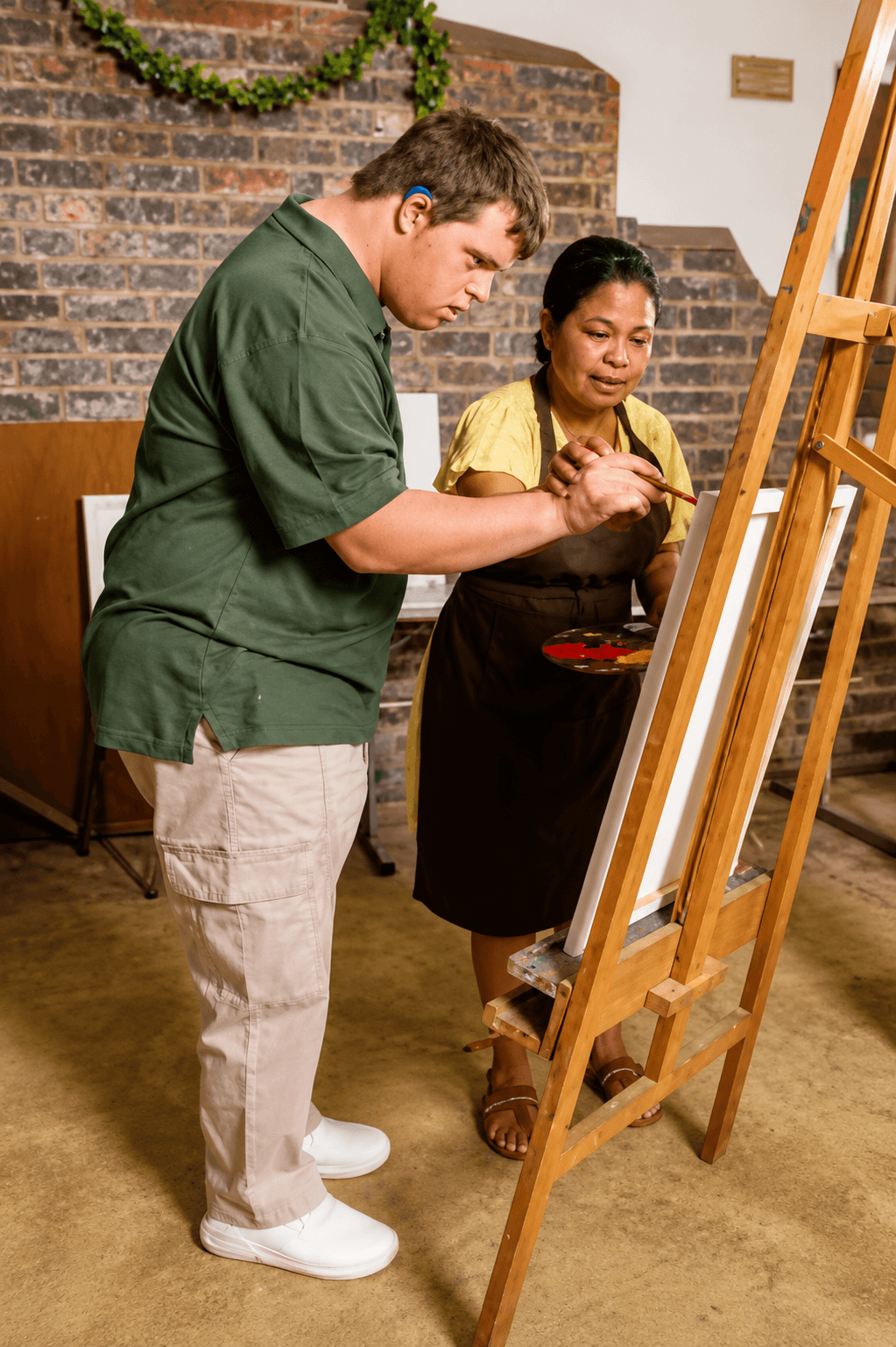 Person painting with guidance from an instructor