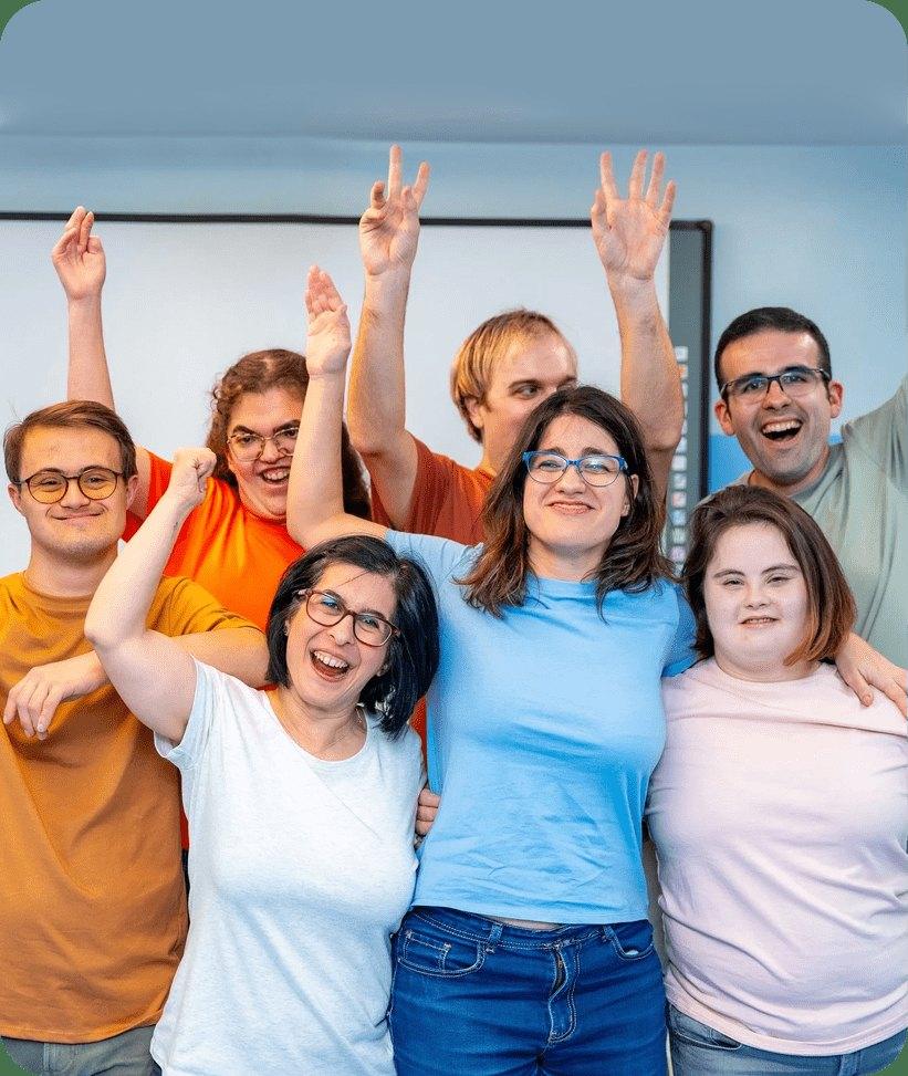 Diverse group of adults smiling and raising their hands together in celebration.